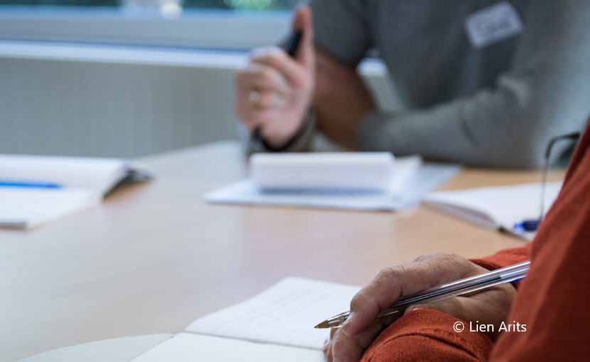 Drie personen vergaderen aan een tafel